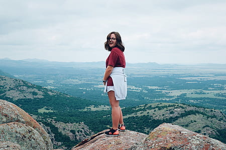 woman in red shirt standing on hill top smiling thumbnail