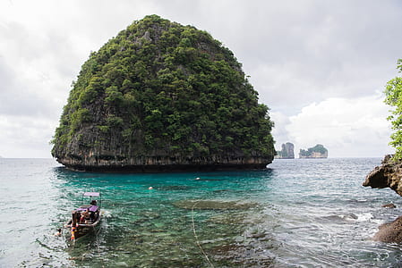 boat towards lush island during daytime thumbnail