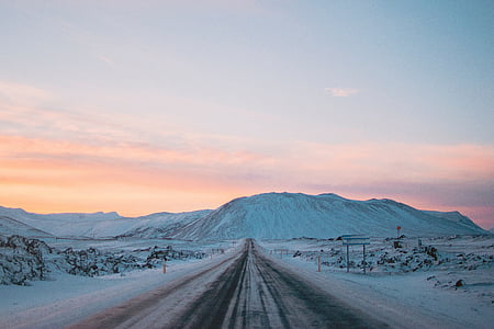 black concrete road near snow covered mountain under white clouds at daytime thumbnail