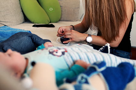Woman Tieing Shoe Near Baby in Blue Stripe Onesie thumbnail