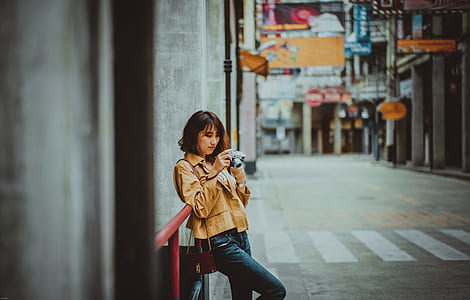 selective focus photography of woman looking on camera while leaning on red metal railing thumbnail