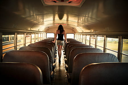woman walking between on bus chairs during daytime thumbnail
