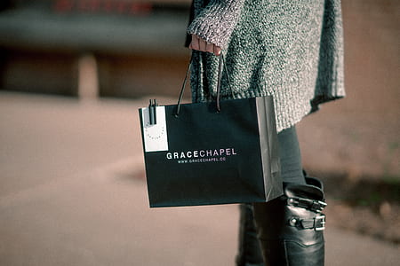 woman holding black Grace Chapel paper bag thumbnail