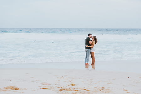 man and woman standing in seashore during daytime thumbnail