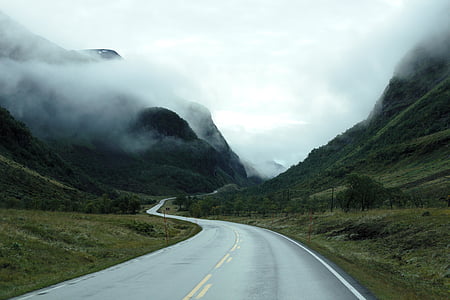 highway in between mountains covered in fog thumbnail