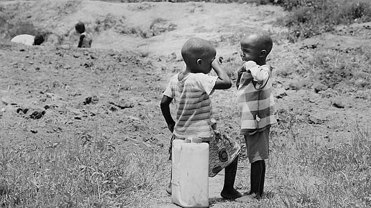 greyscale photo of child sitting on plastic container while wiping eye thumbnail