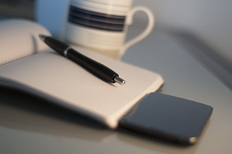 black retractable pen on white ruled paper near mug thumbnail