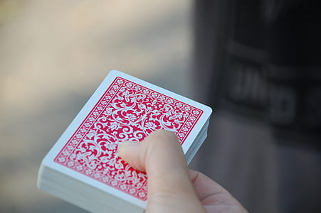 person holding red and white playing card deck thumbnail