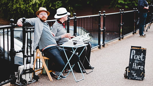 two men sitting on chair while leaning on metal fence thumbnail