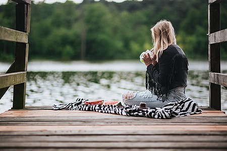 Blonde woman having a healthy snack at the wooden pier thumbnail