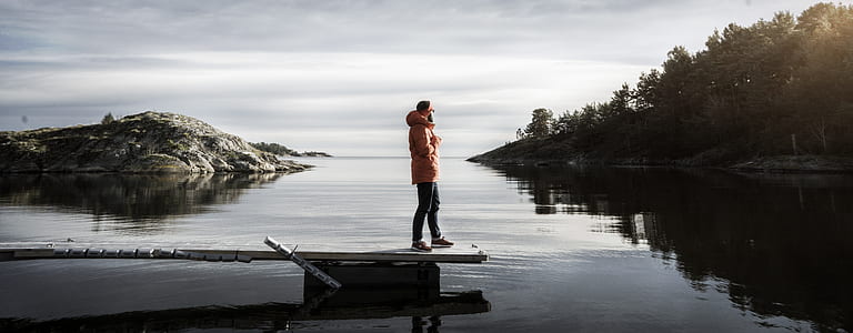 mam standing on dock in middle of body of water during daytime thumbnail