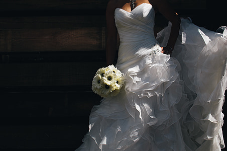 woman wearing wedding dress holding bouquet near wooden wall thumbnail