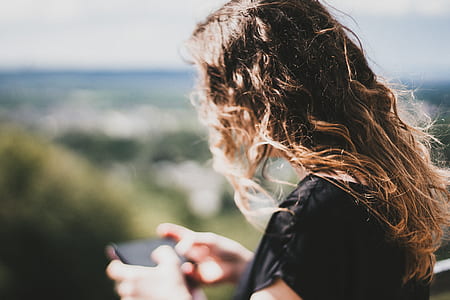 woman in black shirt holding black smartphone thumbnail
