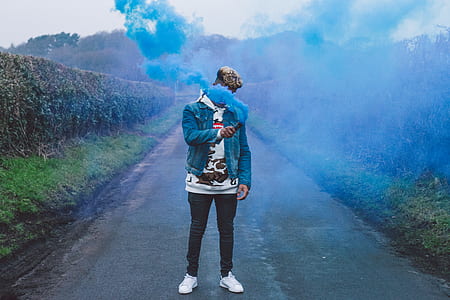 man standing on asphalt road smoking blue smoke bomb thumbnail