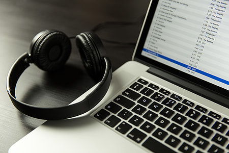 iTunes music app open on a laptop computer alongside headphones thumbnail