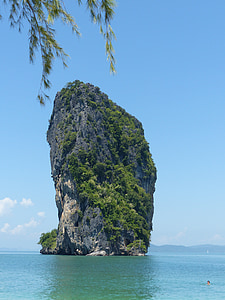 gray rocky monolith covered with green trees and plants thumbnail