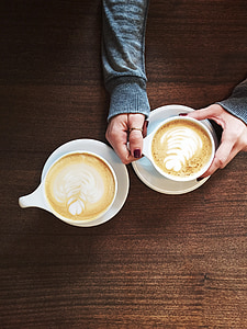 woman holding white ceramic mug on brown wooden surface thumbnail