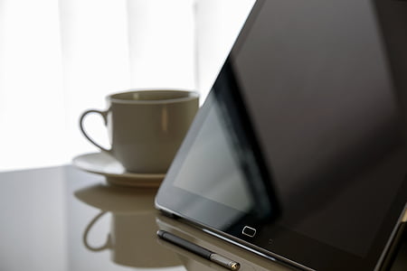 black Samsung Galaxy tablet beside white ceramic cup thumbnail