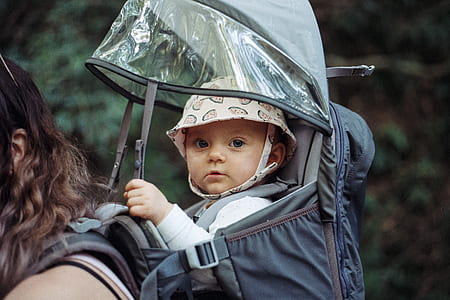 baby wearing brown bucket hat inside black backpack carrier thumbnail