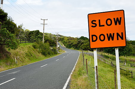 photo of asphalt road beside slow down signboard thumbnail