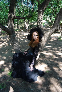 woman wearing black floral long-sleeved gown sitting on tree thumbnail