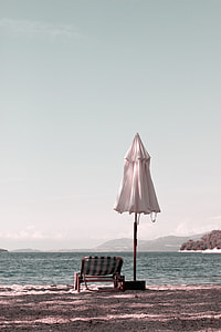brown and white lounge chair near on wide ocean under clear blue sky during daytime thumbnail