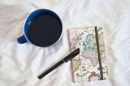 filled cup near pen on map print paper thumbnail