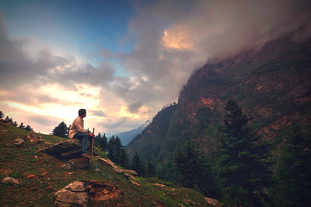 person sitting on rock at hill thumbnail