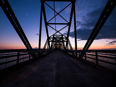 black metal bridge above sea under gray clouds thumbnail