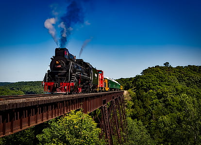 photo of black and white steam train on brown metal bridge taken at daytime thumbnail