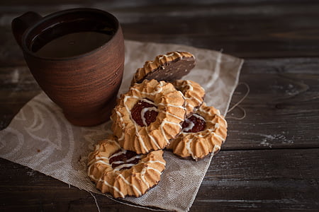 brown ceramic mug beside baked cookies on brown wooden surface thumbnail