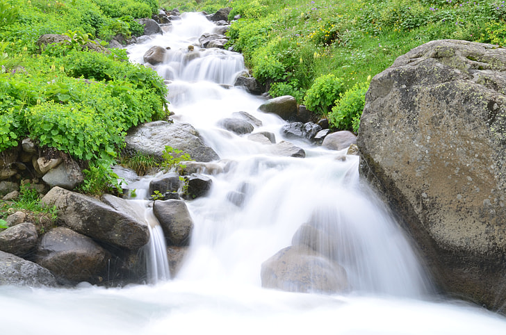 cascading waterfalls in between grass field