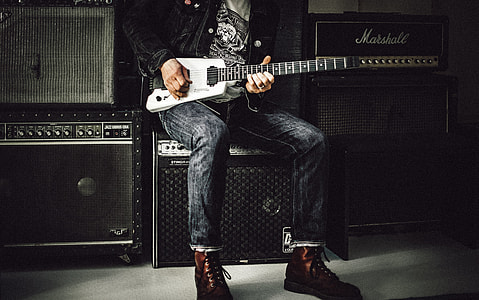 man holding electric guitar near speakers thumbnail