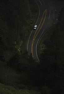 aerial photography of white car cruising road near trees during daytime thumbnail