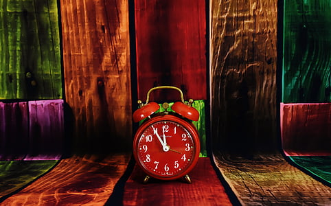 red analog alarm clock on brown wooden surface thumbnail