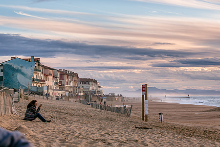 woman in black and gray jacket seated on brown sand during daytime thumbnail