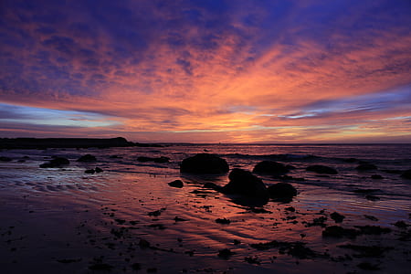 silhouette of rocks on seashore against sunlight thumbnail