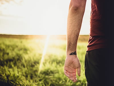 man standing in front of grass field during daytime thumbnail