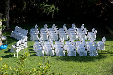 white covered chairs filed horizontally on green lawn thumbnail