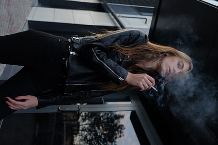 woman in black jacket and pants smoking cigarette thumbnail