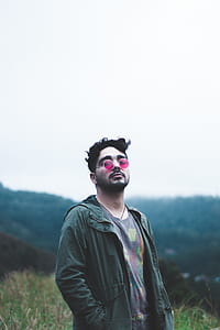 man standing near green grass with mountain background thumbnail
