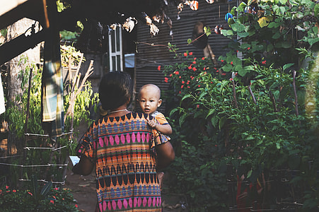 woman carrying toddler near plants thumbnail