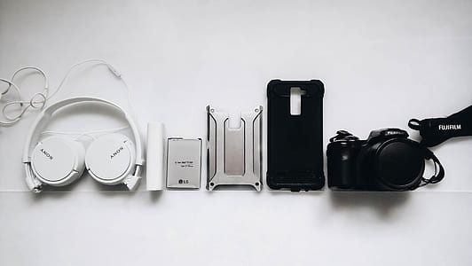 black Fujifilm DSLR camera and white Sony headphones thumbnail