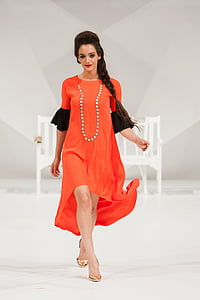 woman wearing orange and black elbow-sleeved maxi dress walking on flooor thumbnail