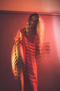 woman wearing orange collared dress standing front of wall thumbnail