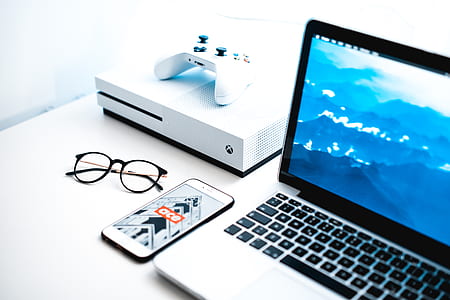 MacBook Pro beside white Microsoft Xbox One on white surface thumbnail