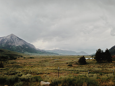 green grass lawn near mountain under white cloudy sky thumbnail