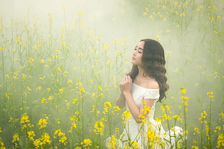 woman wearing white lace off-shoulder dress on yellow rapeseed flower field thumbnail
