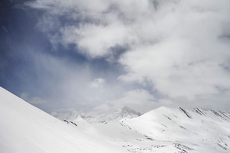 snow-covered mountains under cloudy sky thumbnail