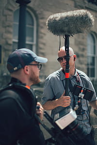 man holding microphone talking to man in black polo shirt thumbnail